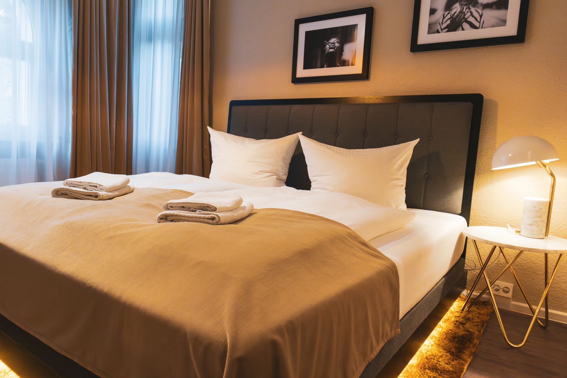 Doppelbett mit weißer Bettwäsche und stilvoller, goldener Nachttischlampe.