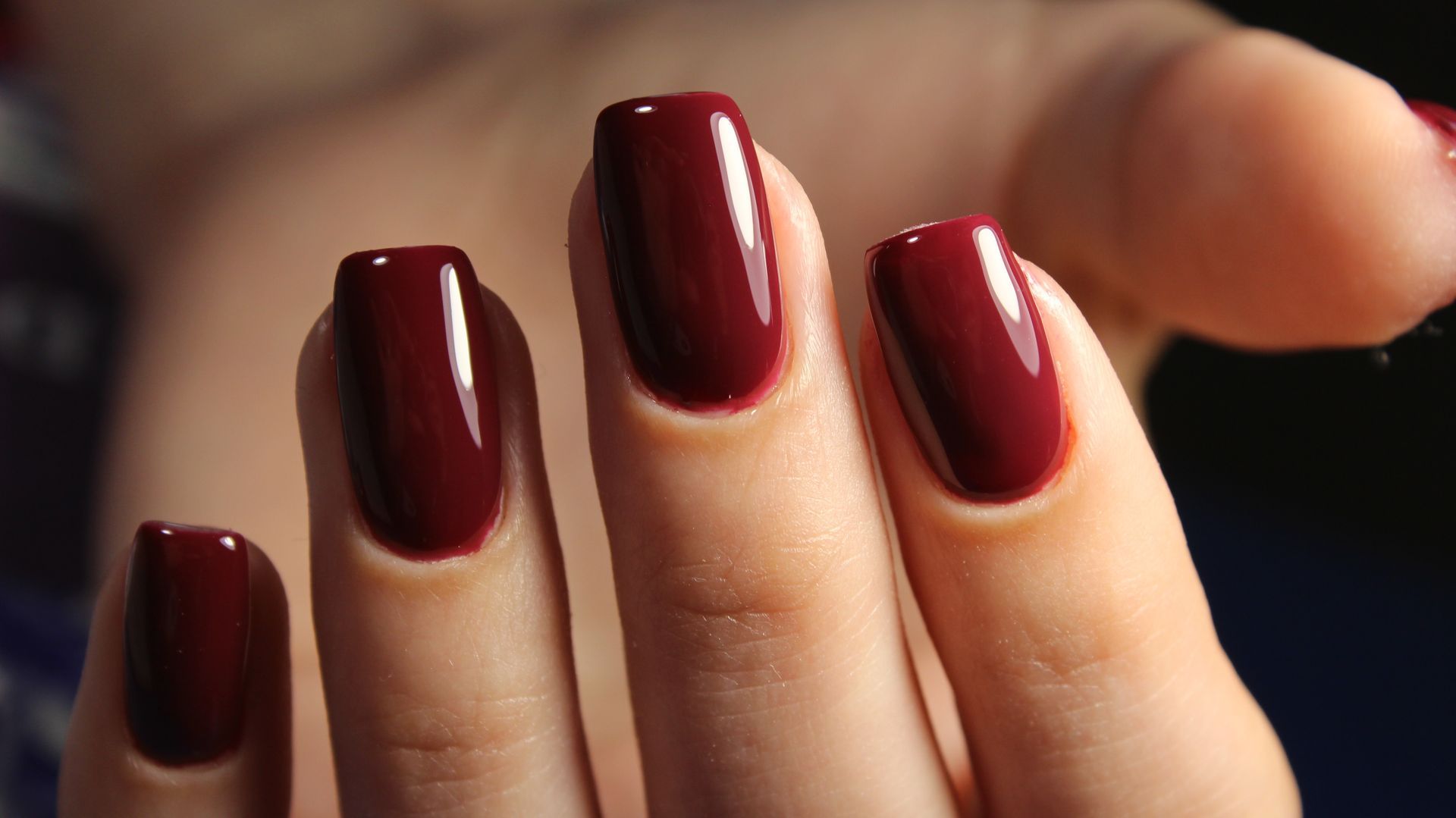 4 doigts d'une main aux ongles vernis de pourpre