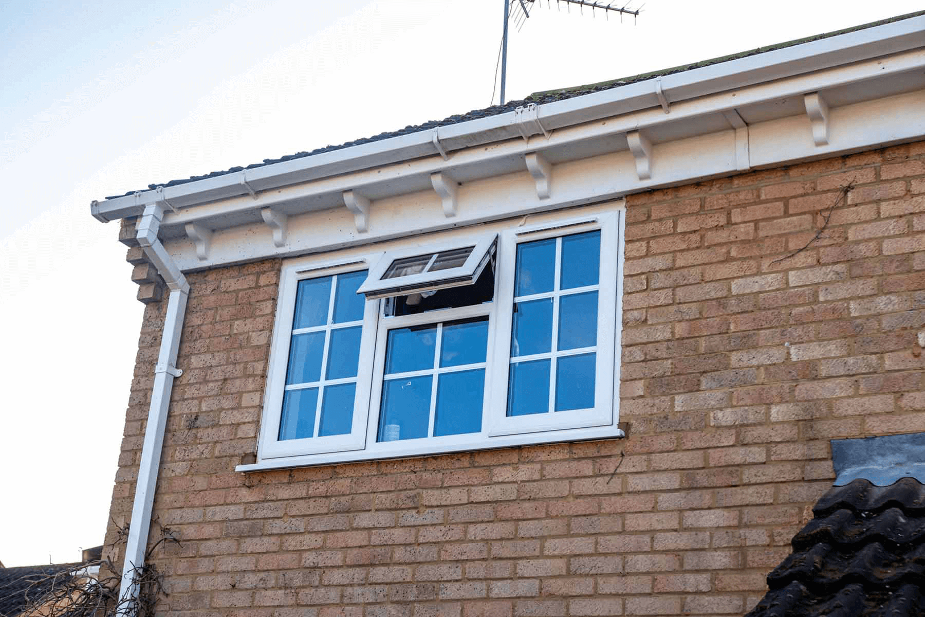 A brick house with a white window on the side of it.