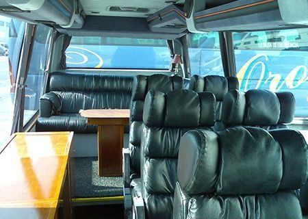 El interior de un autobús con asientos de cuero negro y una mesa.