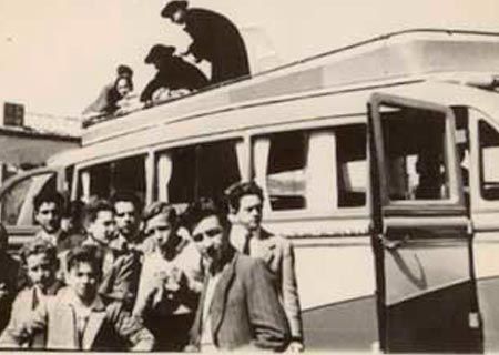 Una fotografía en blanco y negro de un grupo de personas paradas encima de un autobús.