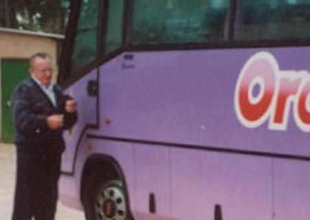 Un hombre parado junto a un autobús morado que dice orco.