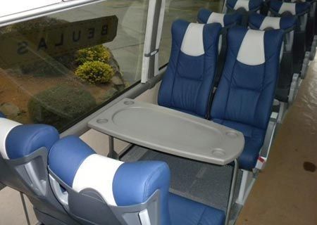 Un autobús con asientos azules y blancos y una mesa
