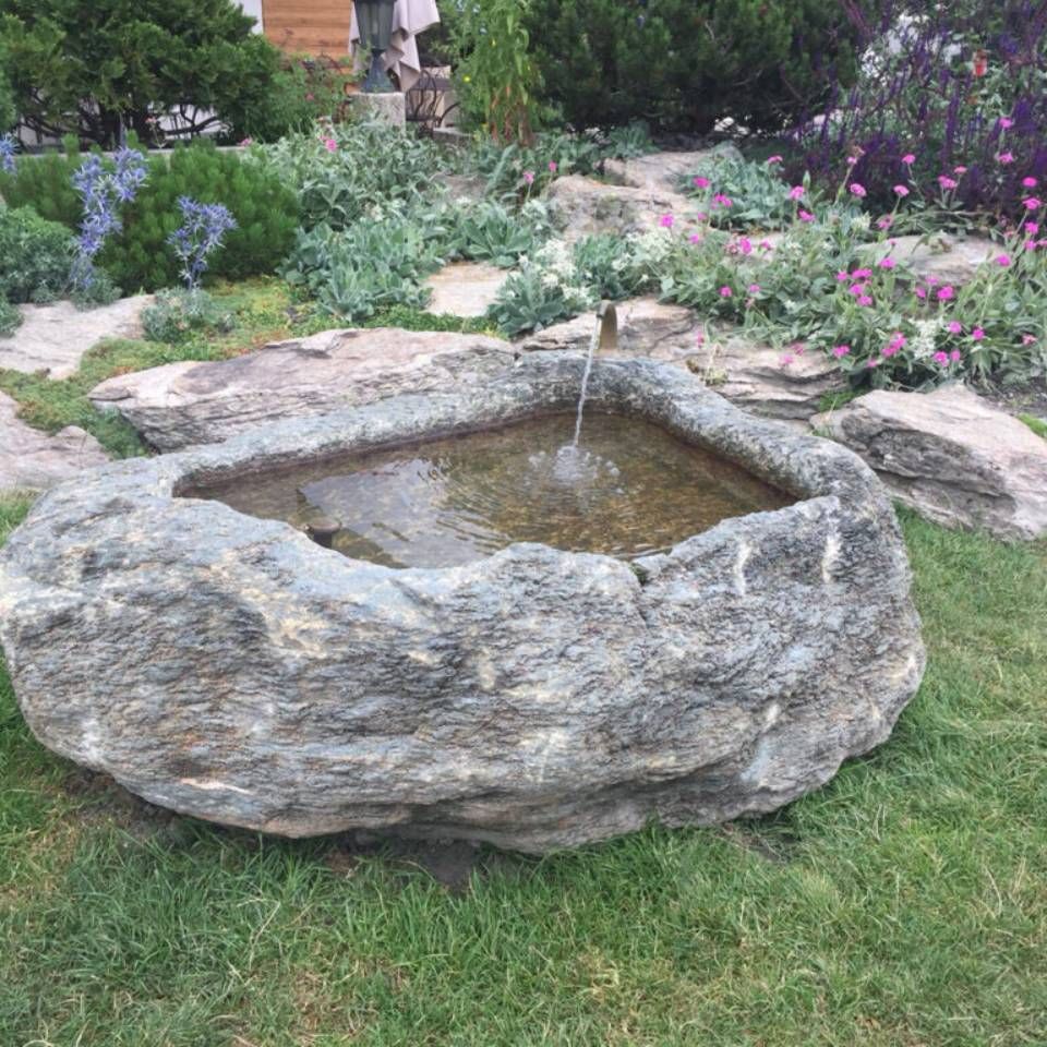 Une grande fontaine rocheuse se trouve au sommet d'une pelouse verdoyante.