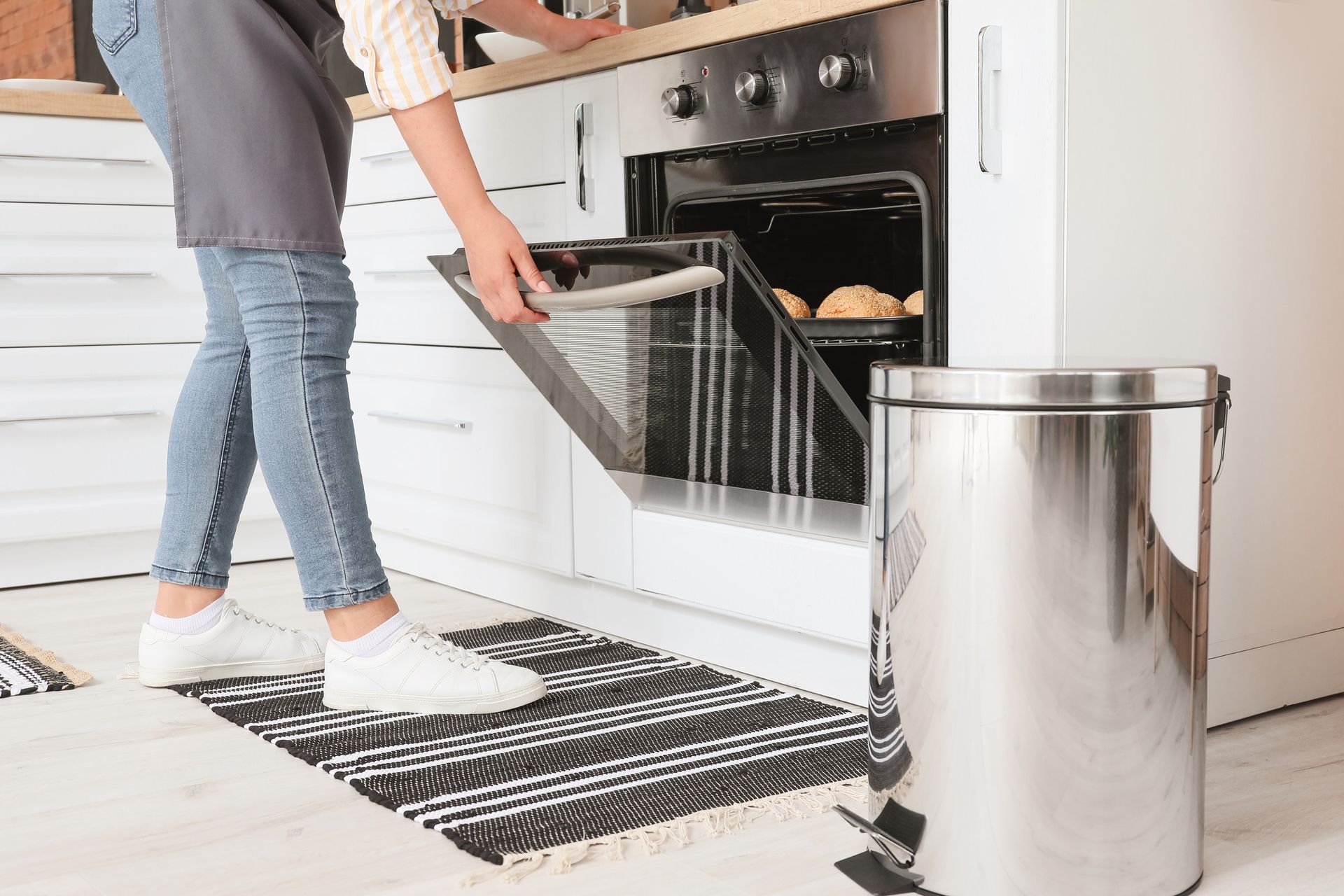 Una mujer está sacando patatas del horno en una cocina.