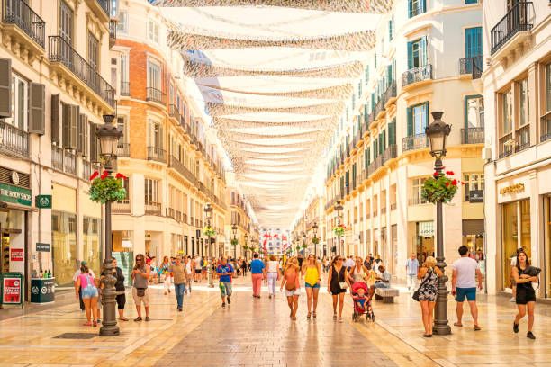 Compradores paseando por un luminoso centro comercial cubierto con toldos blancos colgantes y escaparates a ambos lados.