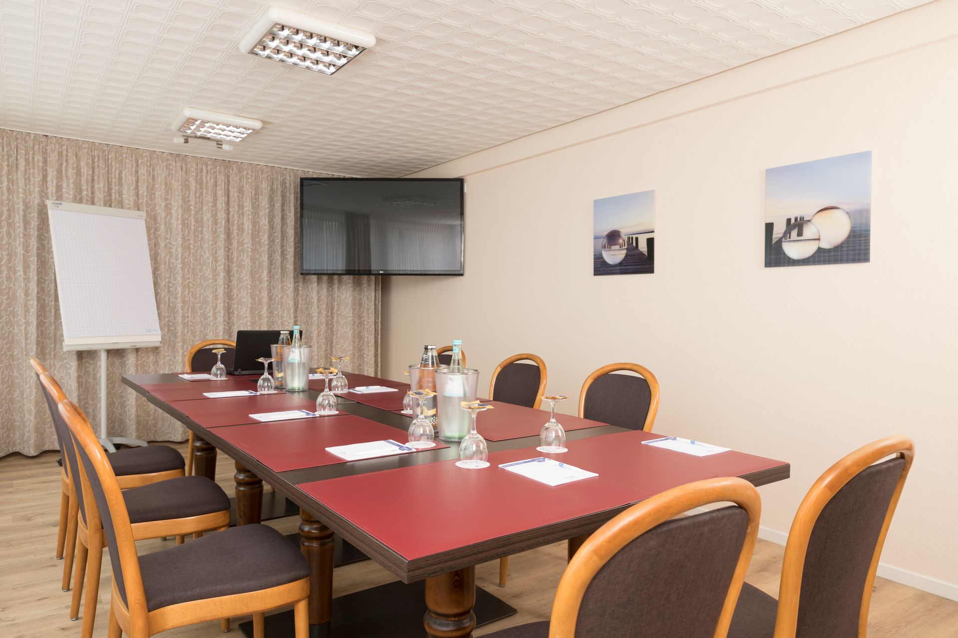 Ein Konferenzraum mit einem langen Tisch und Stühlen sowie einem Flachbildfernseher.