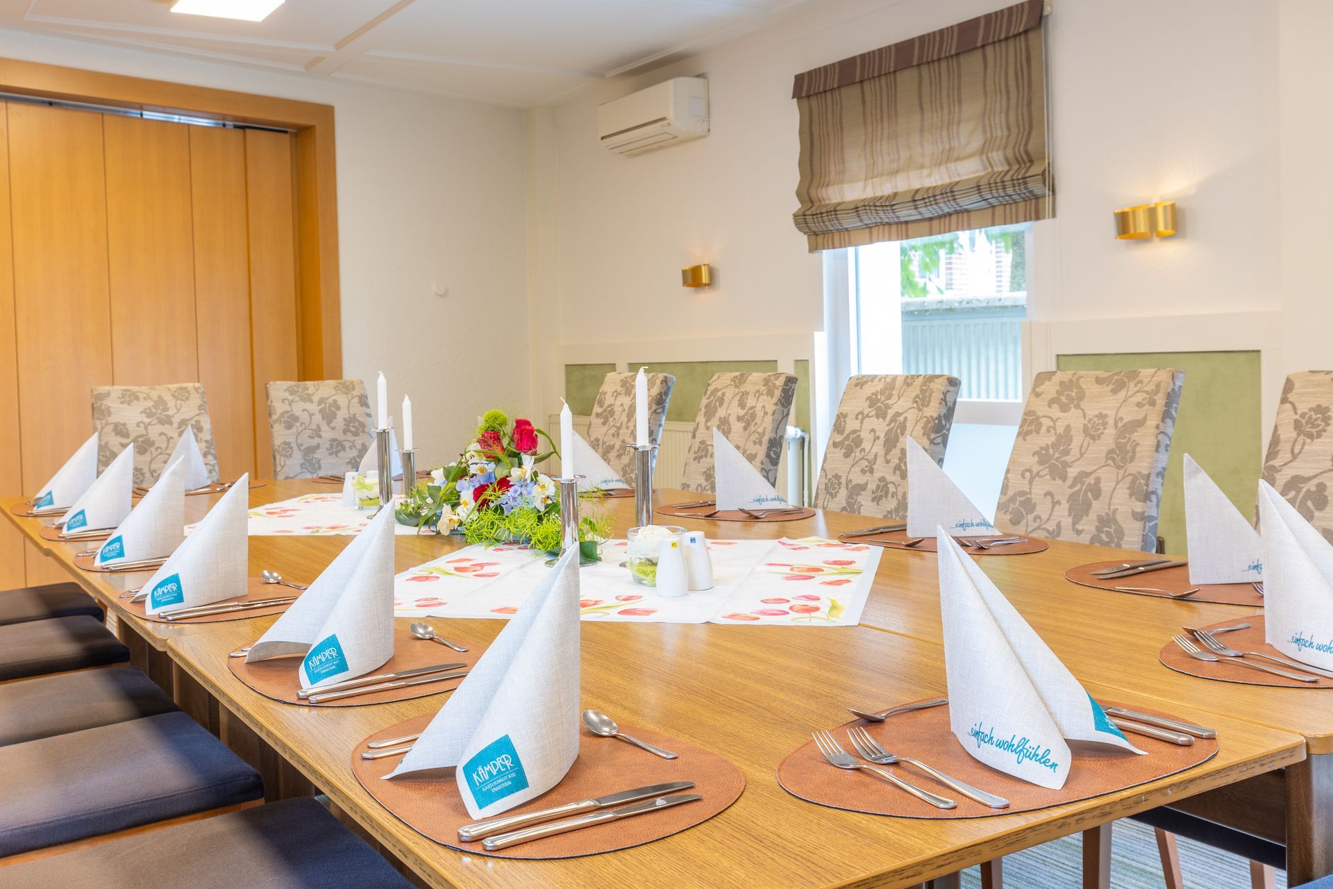 Ein langer Holztisch mit Besteck und Servietten darauf in einem Raum.