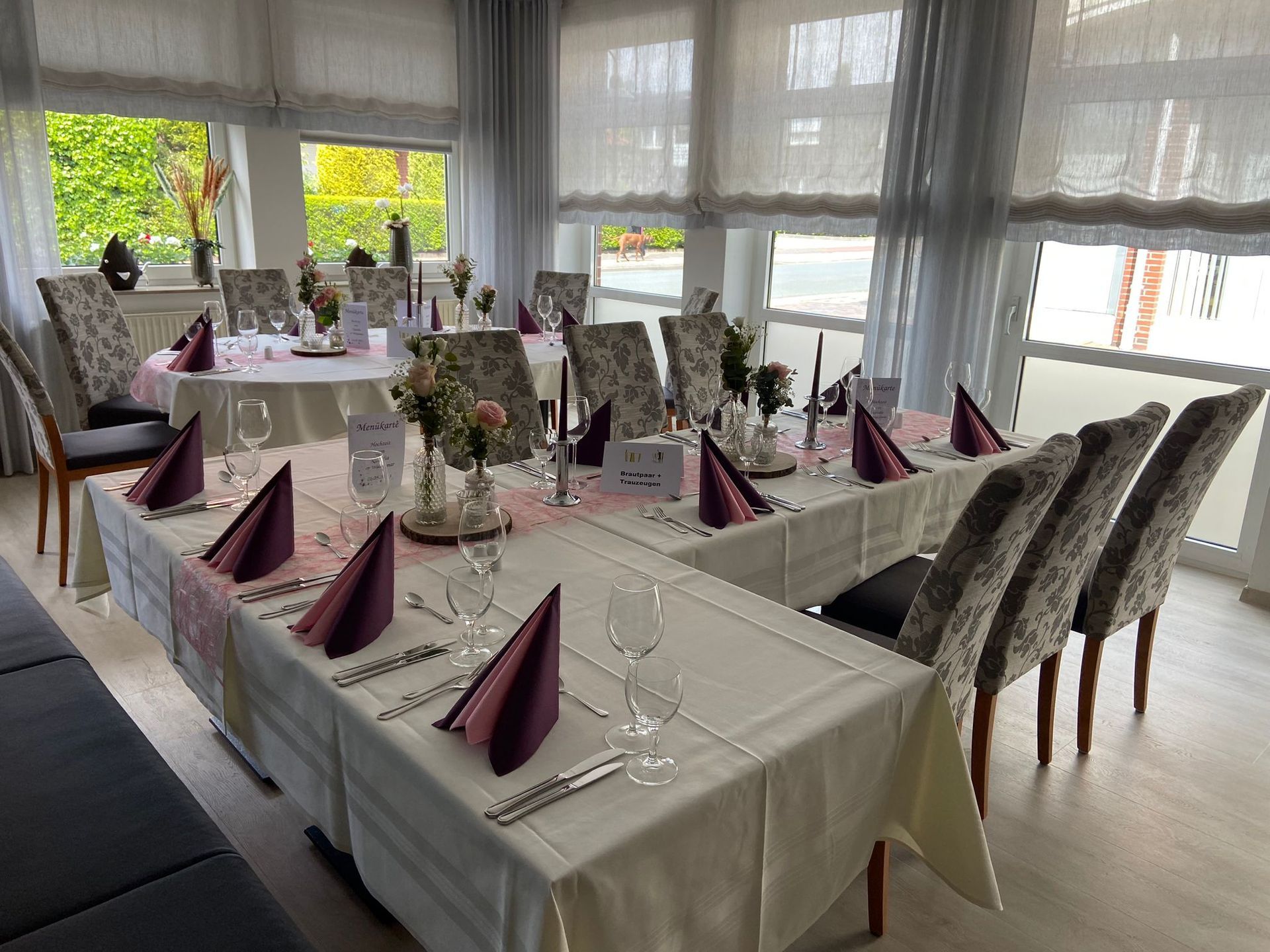 Ein Speisesaal mit Tischen und Stühlen, aufgestellt für einen Hochzeitsempfang.