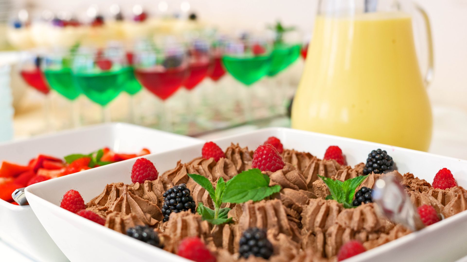 Eine weiße Schüssel gefüllt mit Schokoladenmousse und Beeren auf einem Tisch.