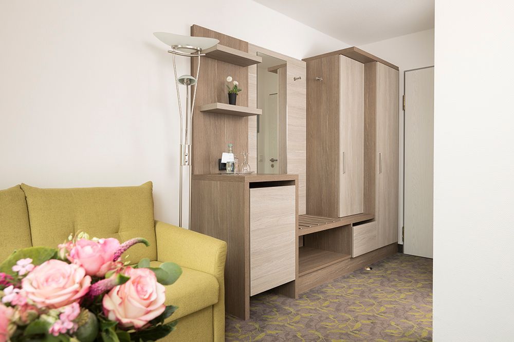 Ein Wohnzimmer mit einem gelben Sofa und einem Strauß rosa Blumen.