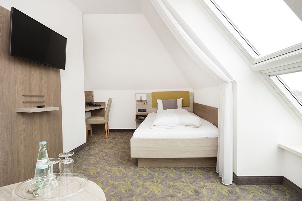 Ein Hotelzimmer mit einem Einzelbett und einem Flachbildfernseher.