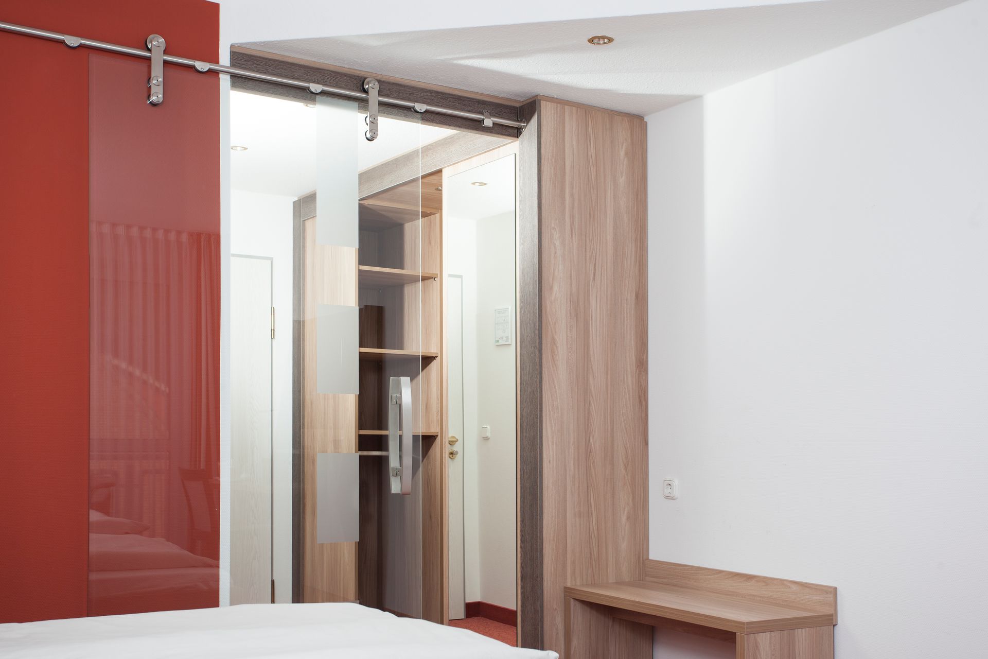 Ein Schlafzimmer mit einer Glasschiebetür, die zu einem begehbaren Kleiderschrank führt.