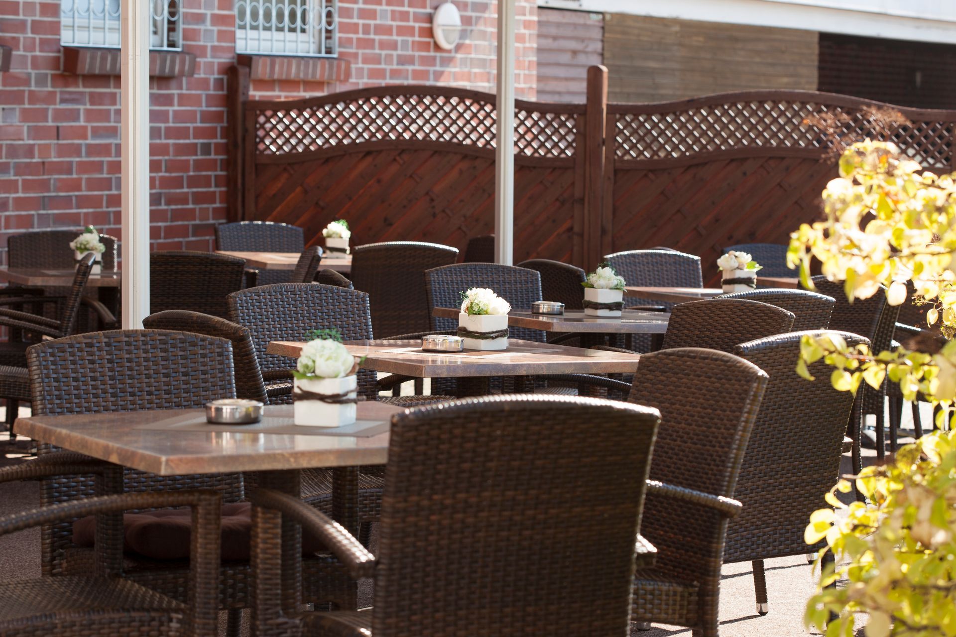 Eine Terrasse mit Tischen und Stühlen vor einem Backsteingebäude