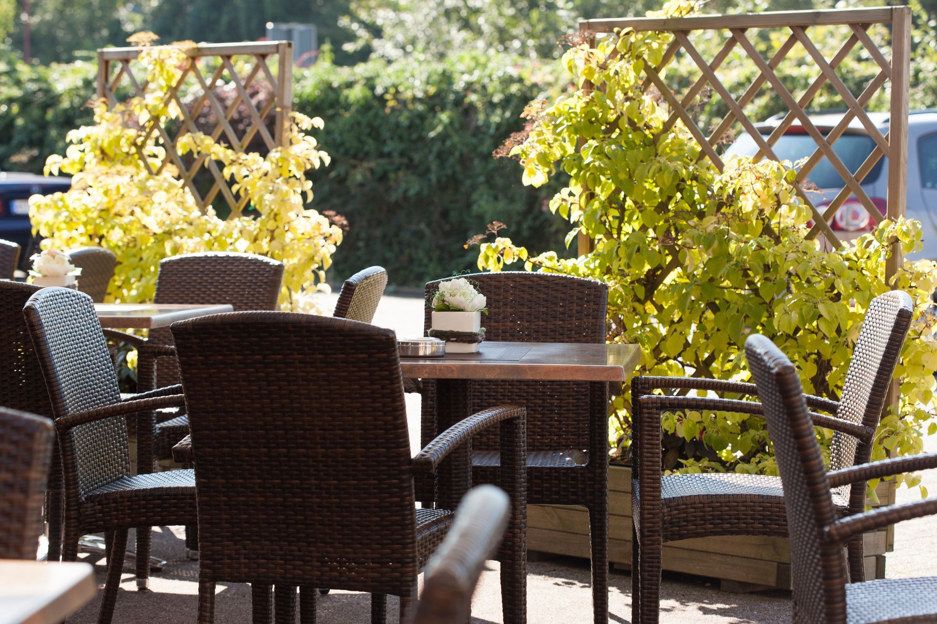 Eine Terrasse mit Tischen und Stühlen, umgeben von Pflanzen