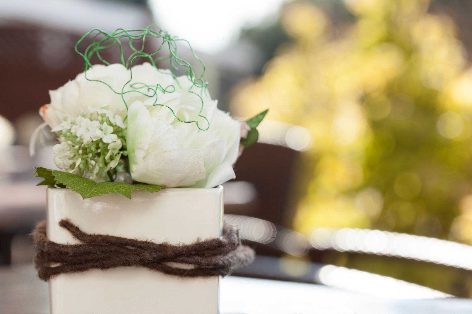 Auf einem Tisch steht eine weiße Vase mit weißen Blumen.