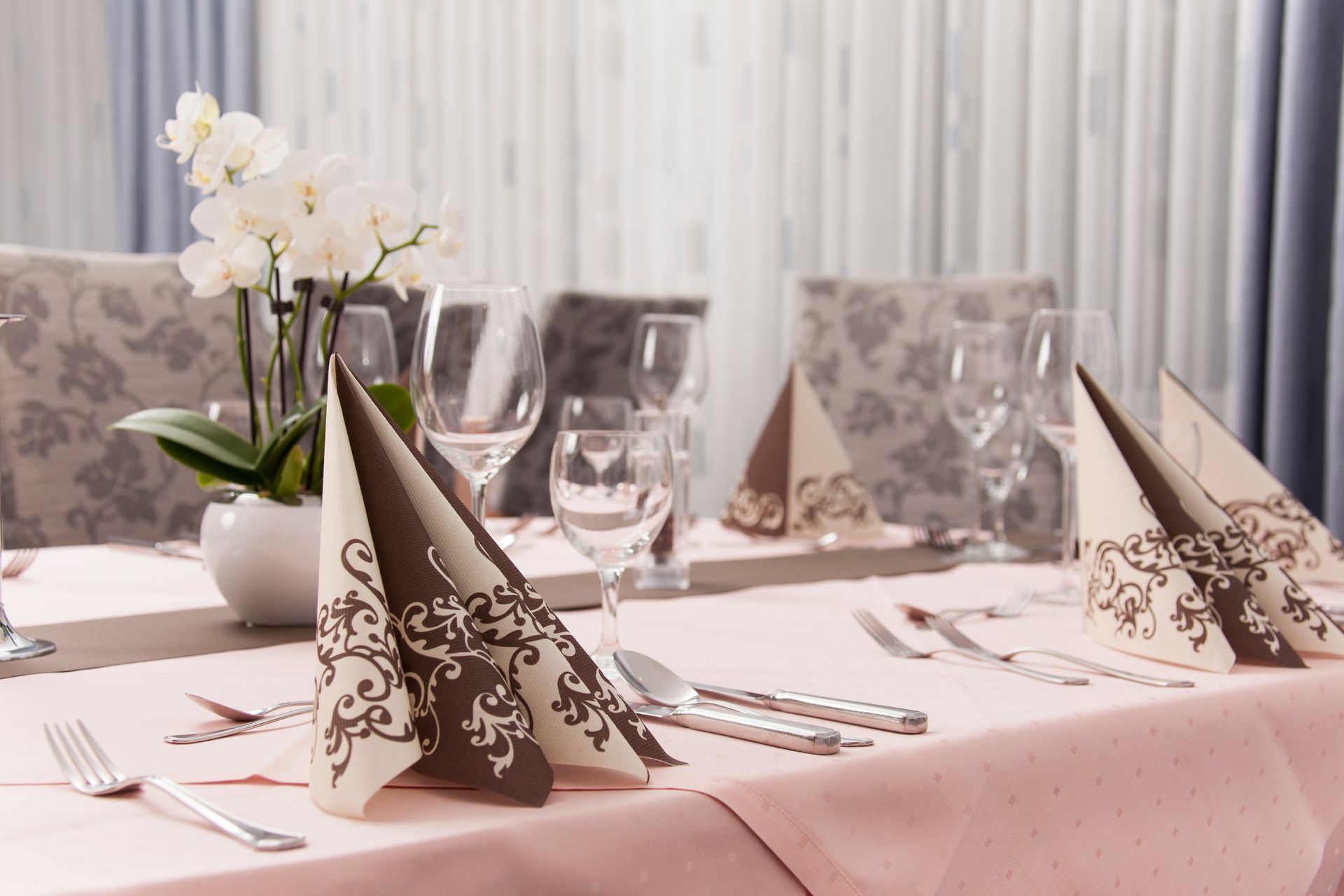 Ein Tisch mit einer rosa Tischdecke und einer Vase mit Blumen darauf