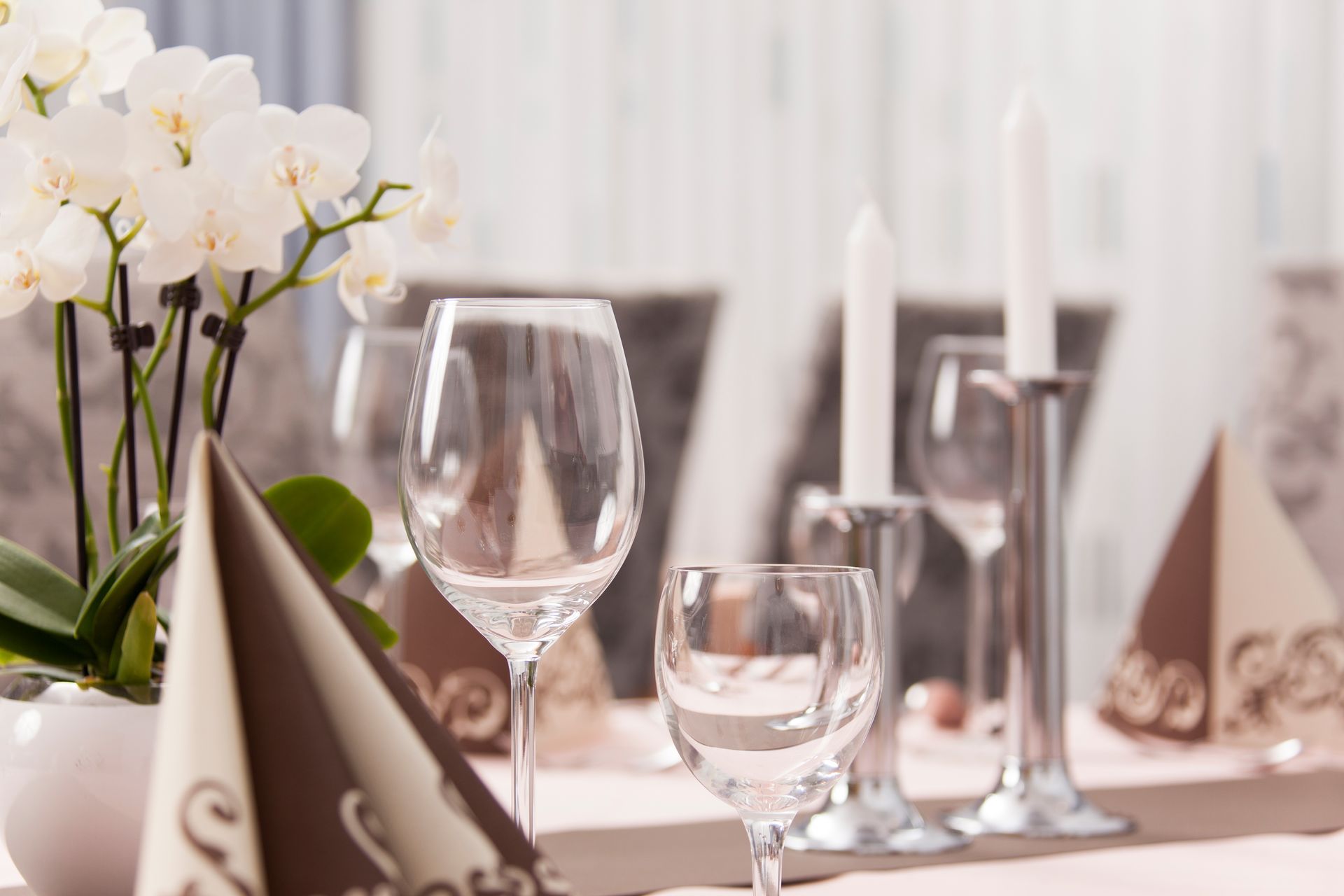 Ein für eine Dinnerparty gedeckter Tisch mit Weingläsern, Kerzen und Blumen.