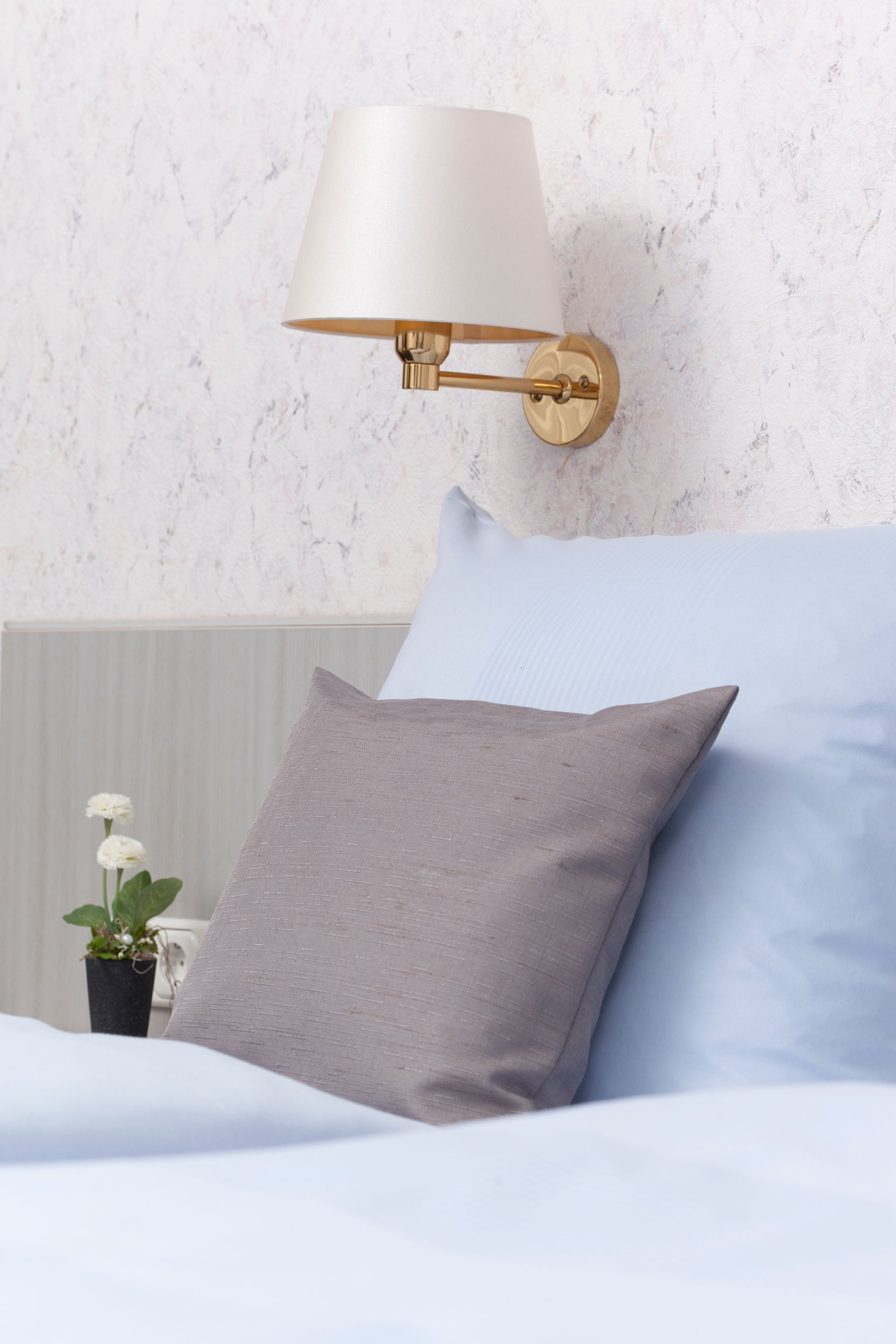 Ein Bett mit Kissen und einer Lampe an der Wand