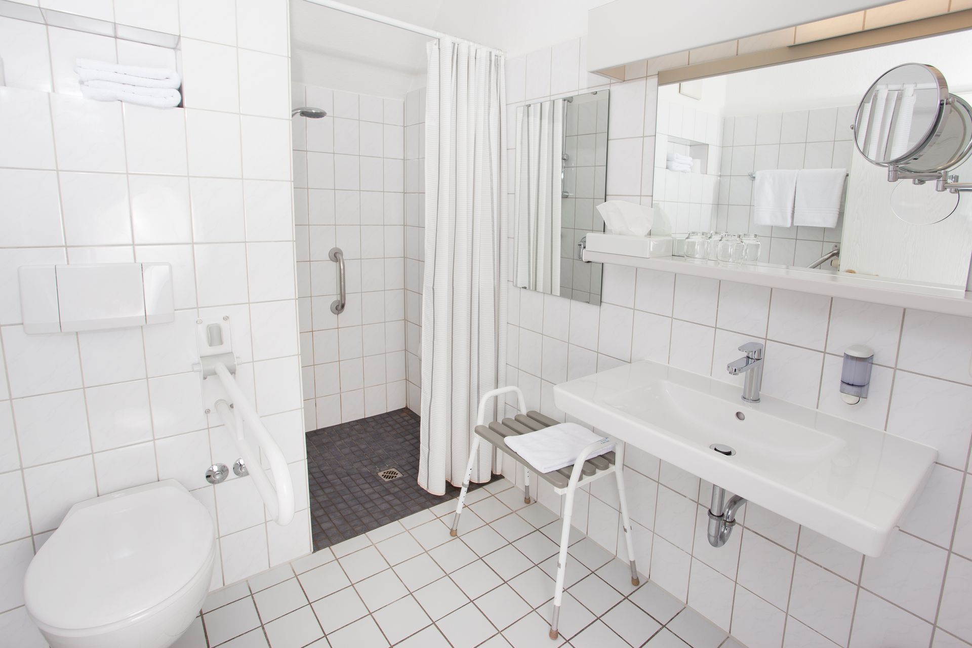Ein Badezimmer mit Toilette, Waschbecken, Spiegel und Dusche.