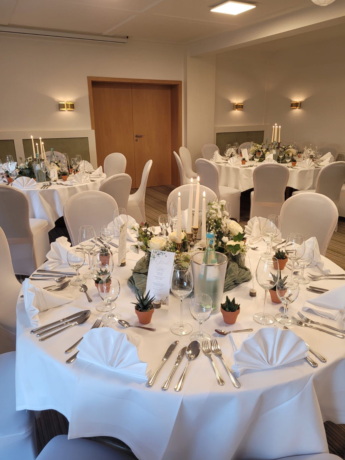 Ein Raum voller Tische und Stühle, aufgestellt für einen Hochzeitsempfang.