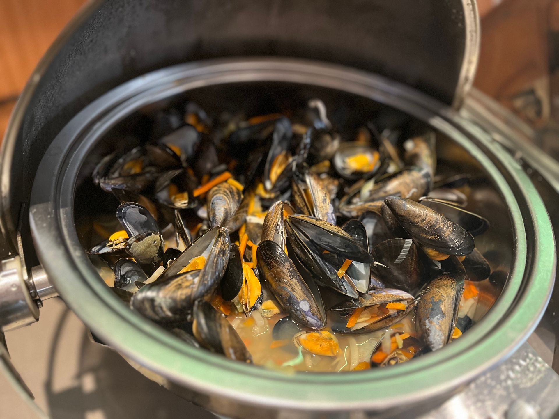 Eine Schüssel Muscheln in Soße auf einem Buffet-Tisch.
