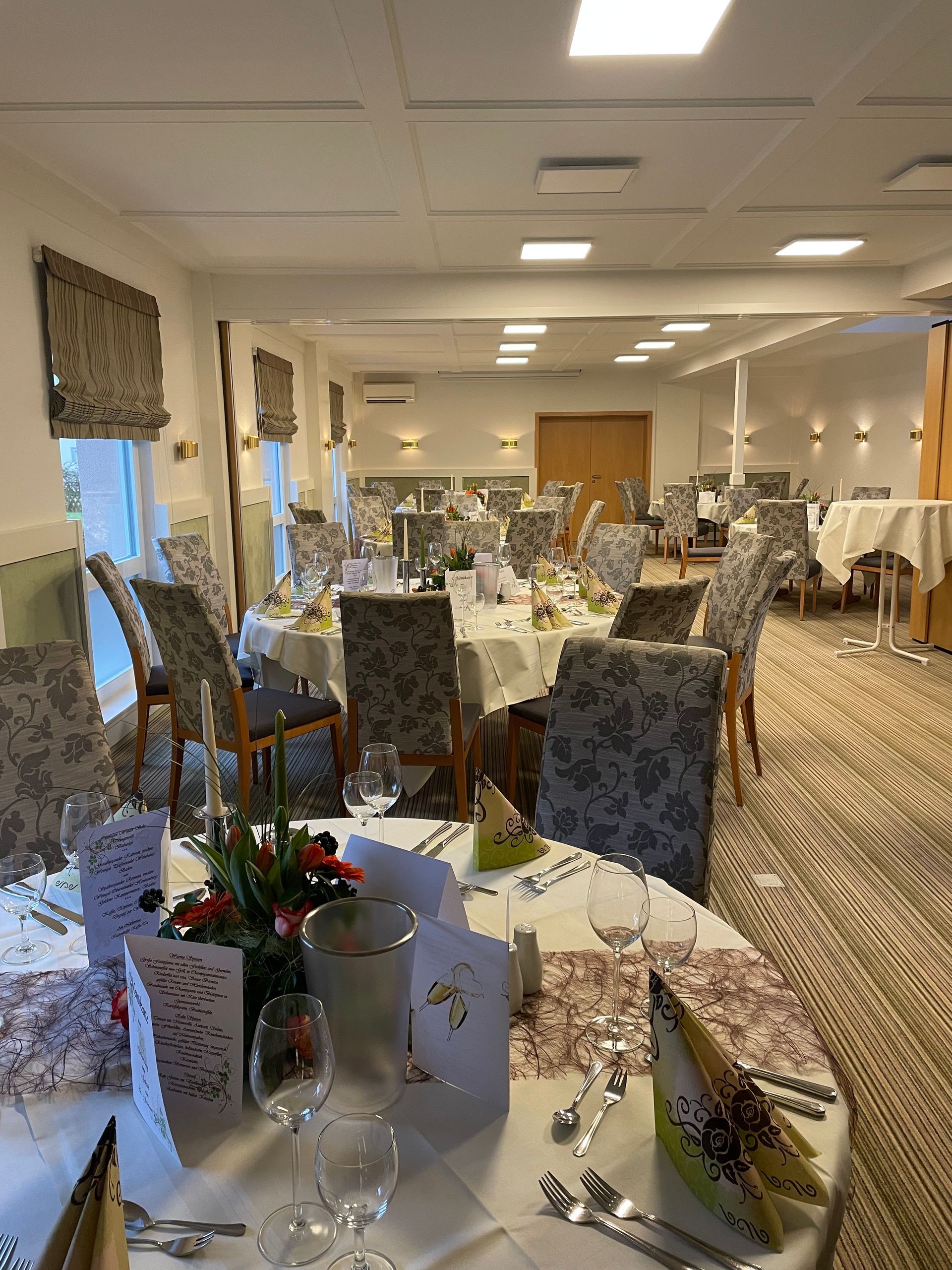 Ein großer Raum mit Tischen und Stühlen für einen Hochzeitsempfang.