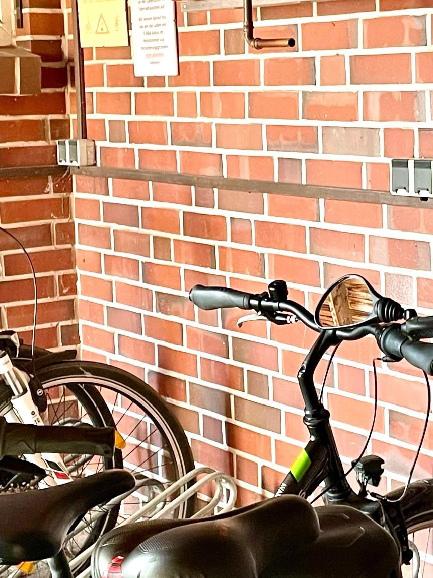 Vor einer Backsteinmauer stehen zwei Fahrräder.
