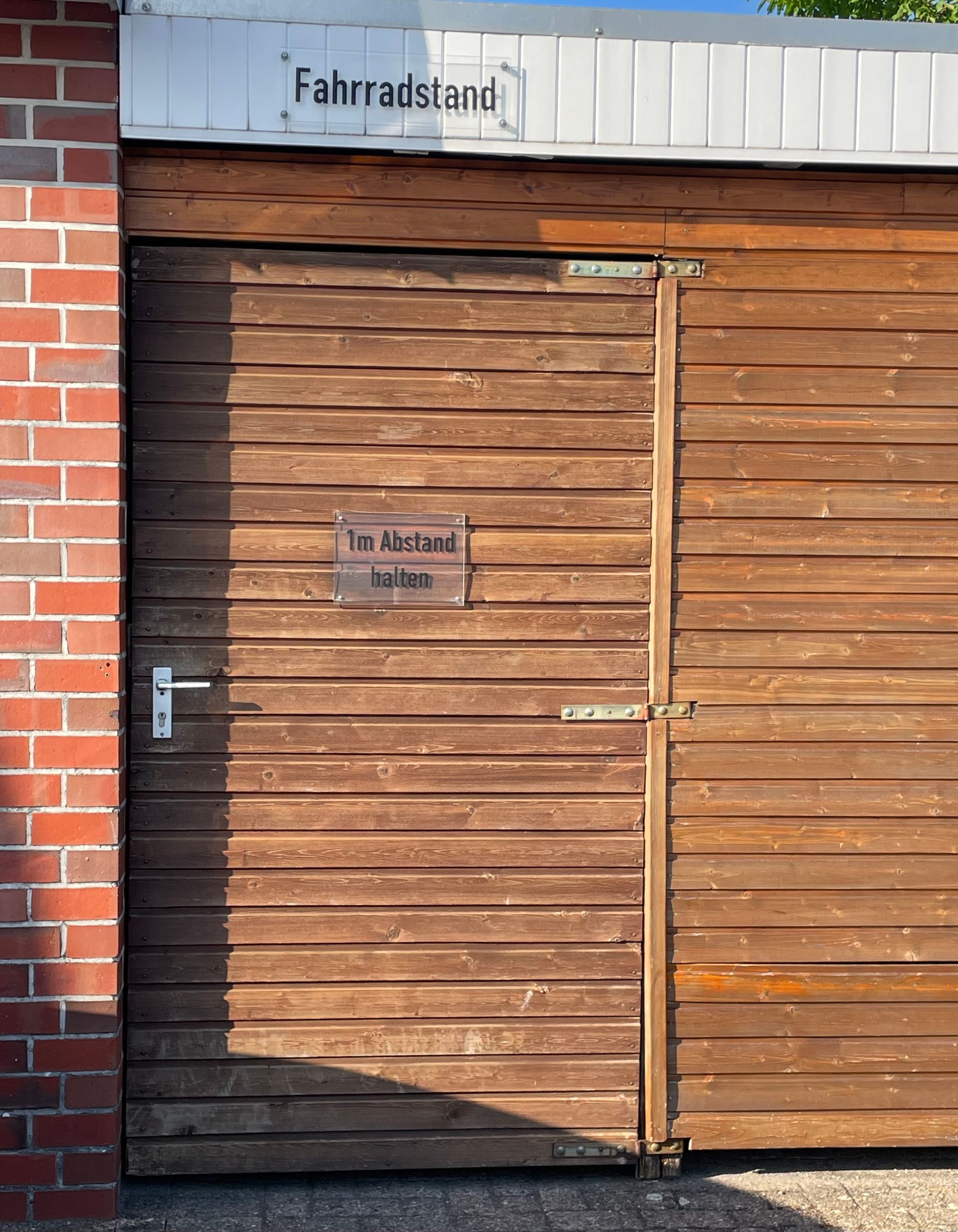 Ein hölzernes Garagentor mit einem Schild darauf, auf dem steht „Fahrradstand“