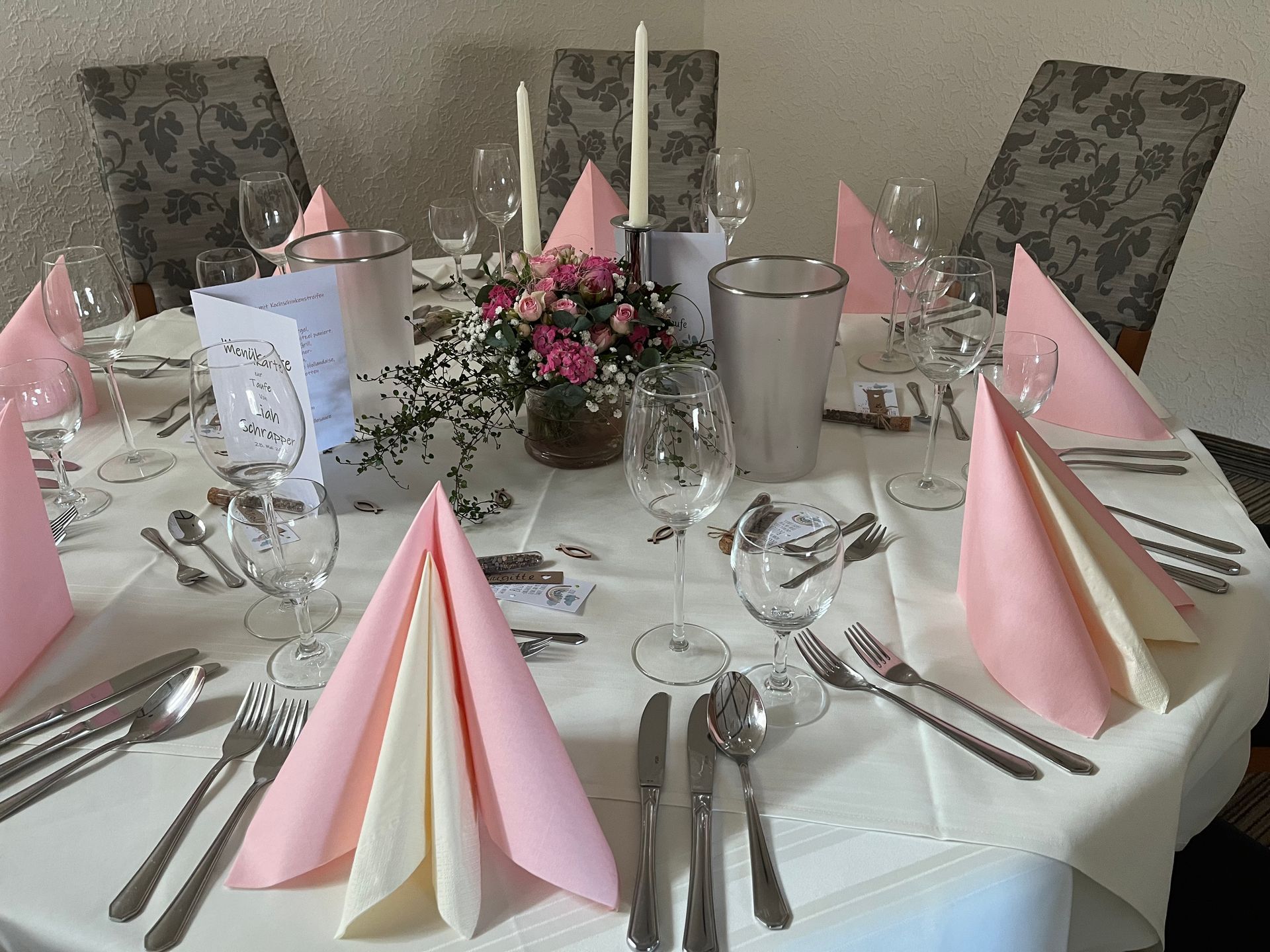 Ein für einen Hochzeitsempfang gedeckter Tisch mit rosa Servietten und Kerzen