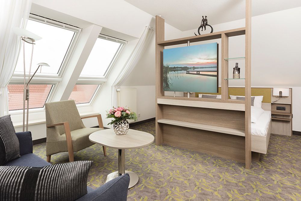 Ein Wohnzimmer mit Couch, Sessel, Tisch und Fernseher.