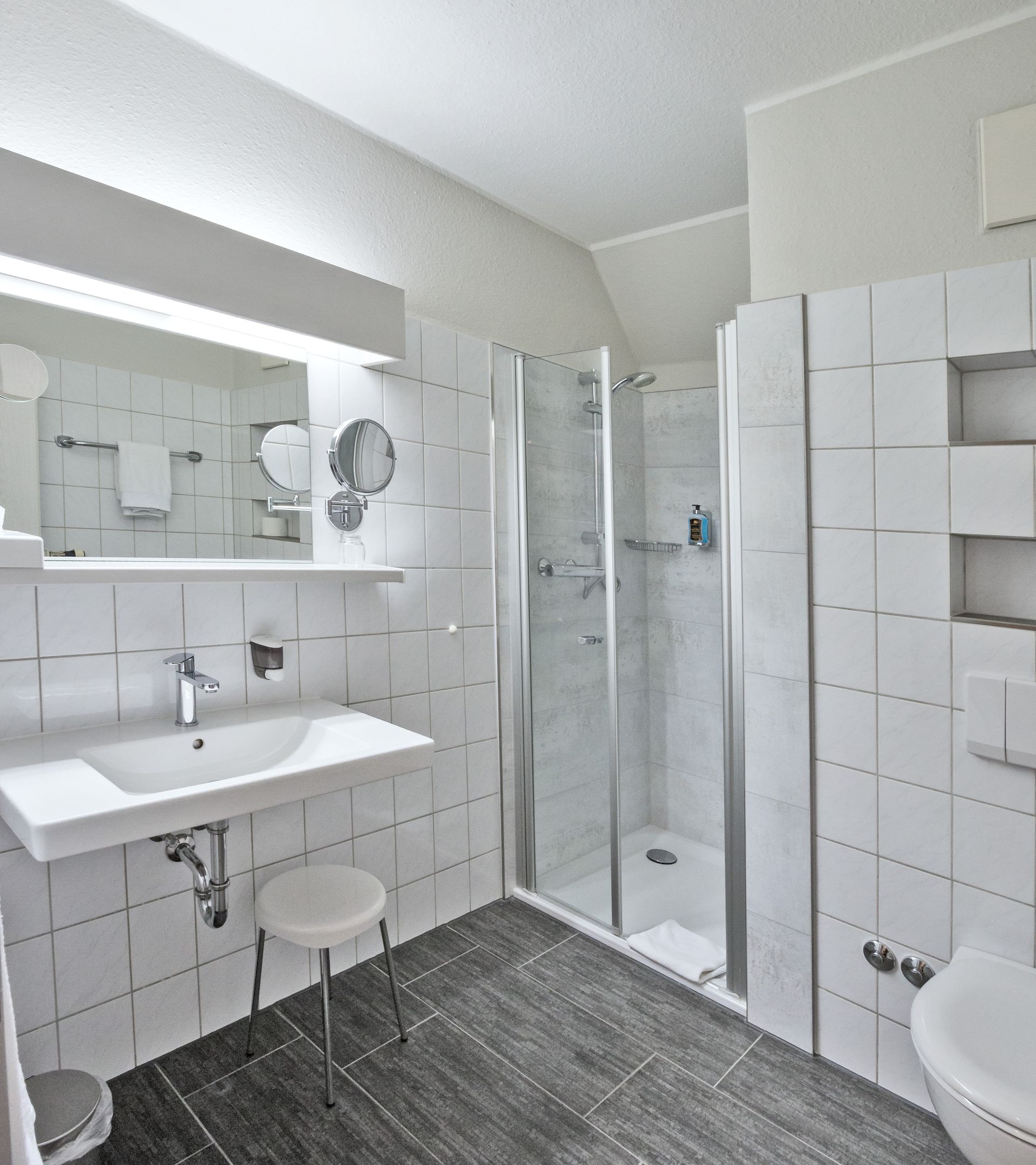 Ein Badezimmer mit Waschbecken, Toilette und ebenerdiger Dusche