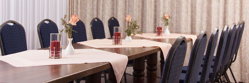 Ein langer Tisch mit einer Vase voller Blumen darauf in einem Konferenzraum.