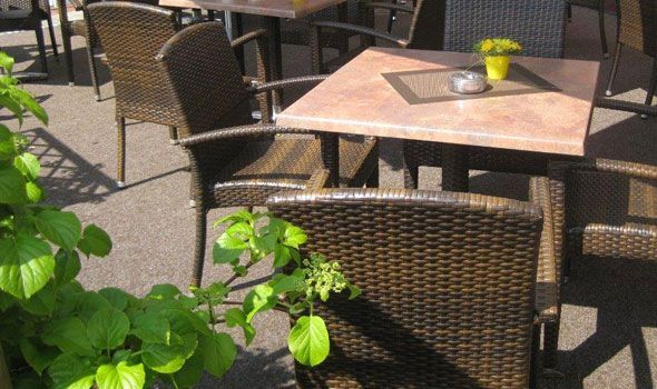 Eine Terrasse mit Korbstühlen und Tischen an einem sonnigen Tag