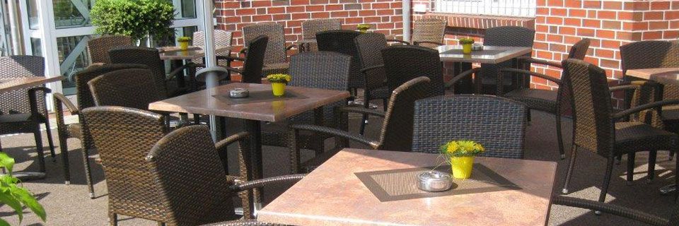 Eine Terrasse mit Tischen und Stühlen vor einem Backsteingebäude