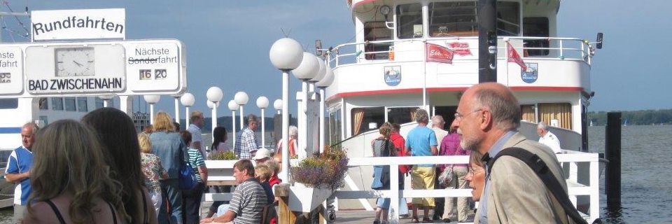 Eine Gruppe von Leuten steht auf einem Dock neben einem Boot.