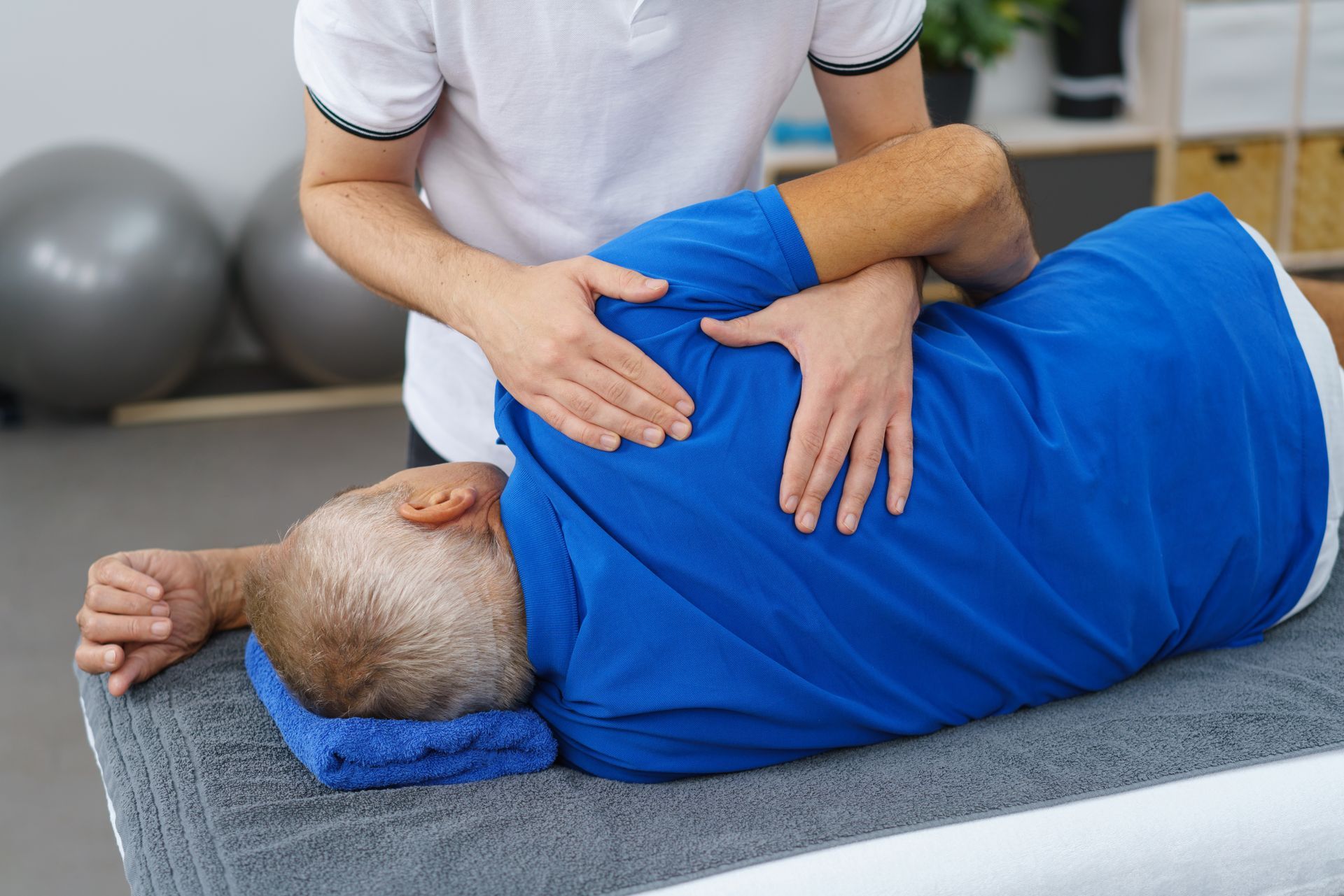 Eine Person erhält in einem hellen Behandlungsraum eine Rückenmassage mit warmem Öl auf einer Spa-Liege.