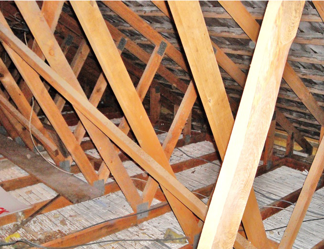 Charpente en bois avec poutres orange et claires dans un espace sous les combles