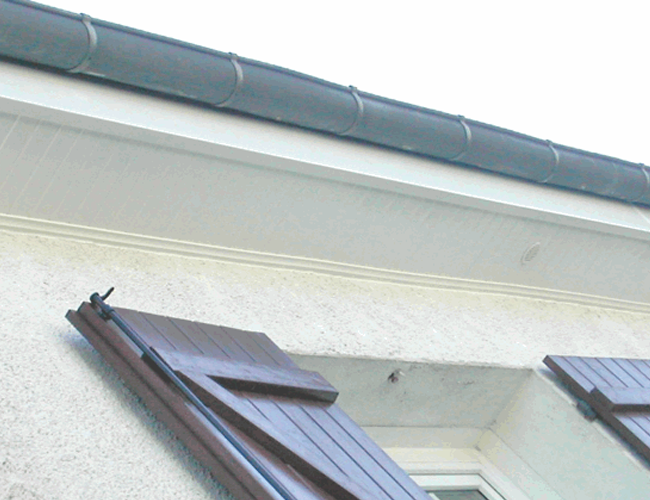Volets en bois ouverts sur la façade d'une maison blanche, sous une gouttière grise