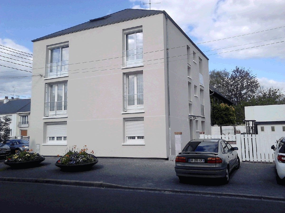 Immeuble d'appartements moderne de trois étages avec voitures garées et ciel nuageux
