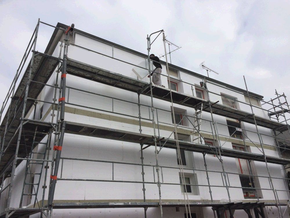 Échafaudages autour d'un bâtiment blanc en construction par temps couvert