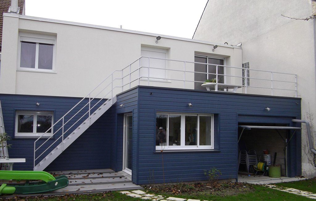 Maison bleue et blanche avec escalier, fenêtres et petite terrasse.