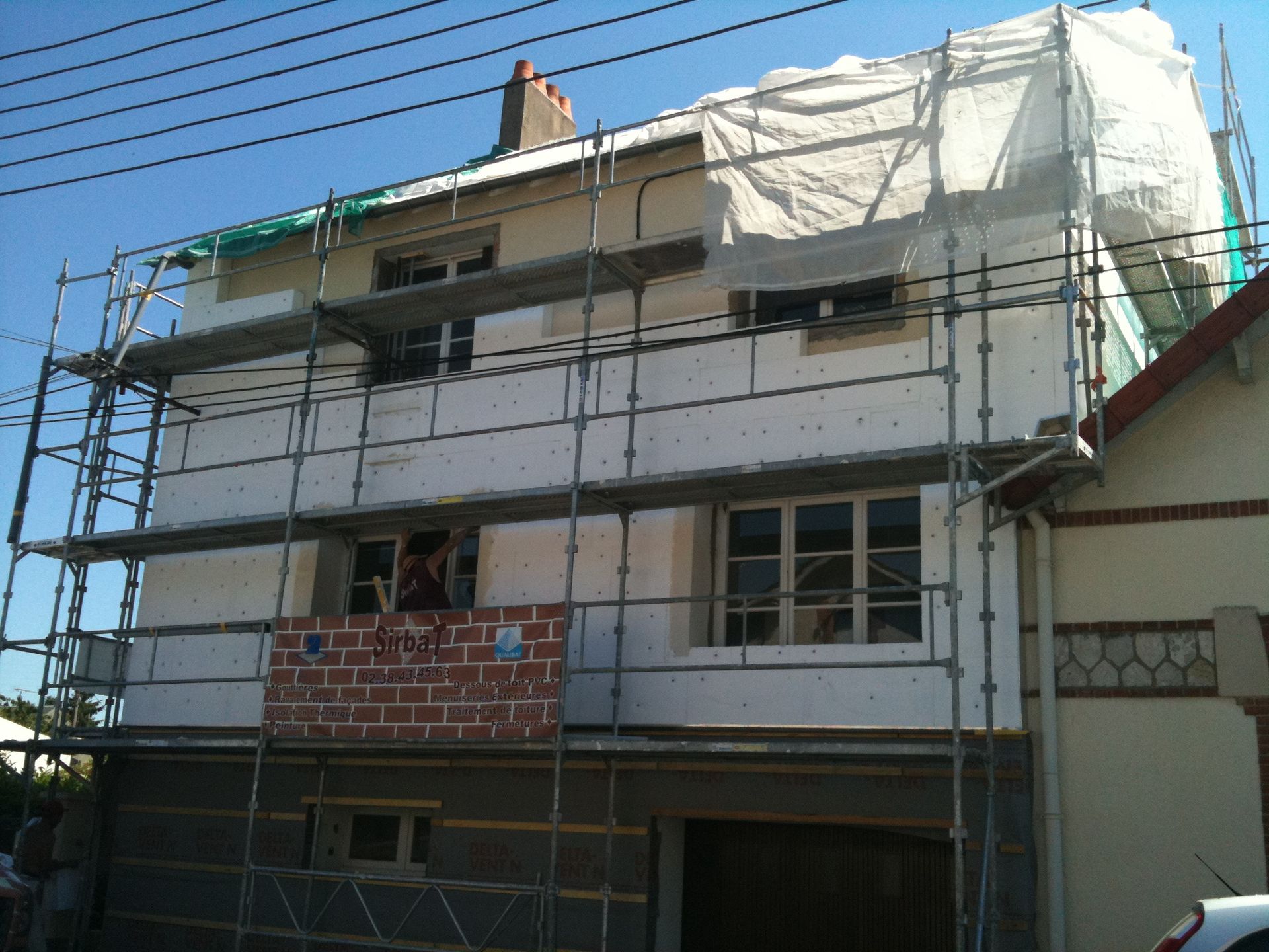 Maison en rénovation avec échafaudages et filets de protection à l'extérieur