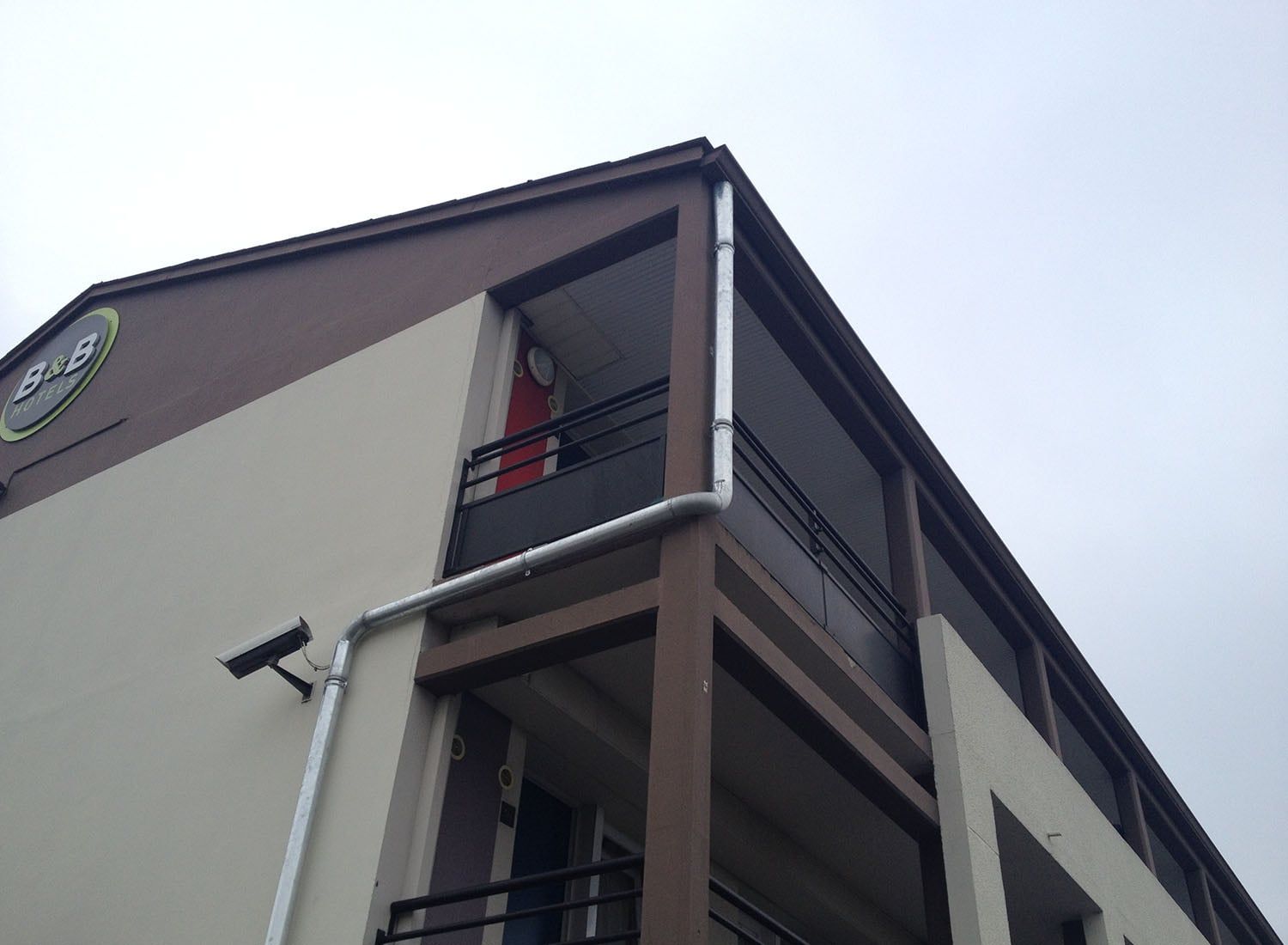 Extérieur d'un immeuble à plusieurs étages avec balcons et une chaise rouge à un étage supérieur