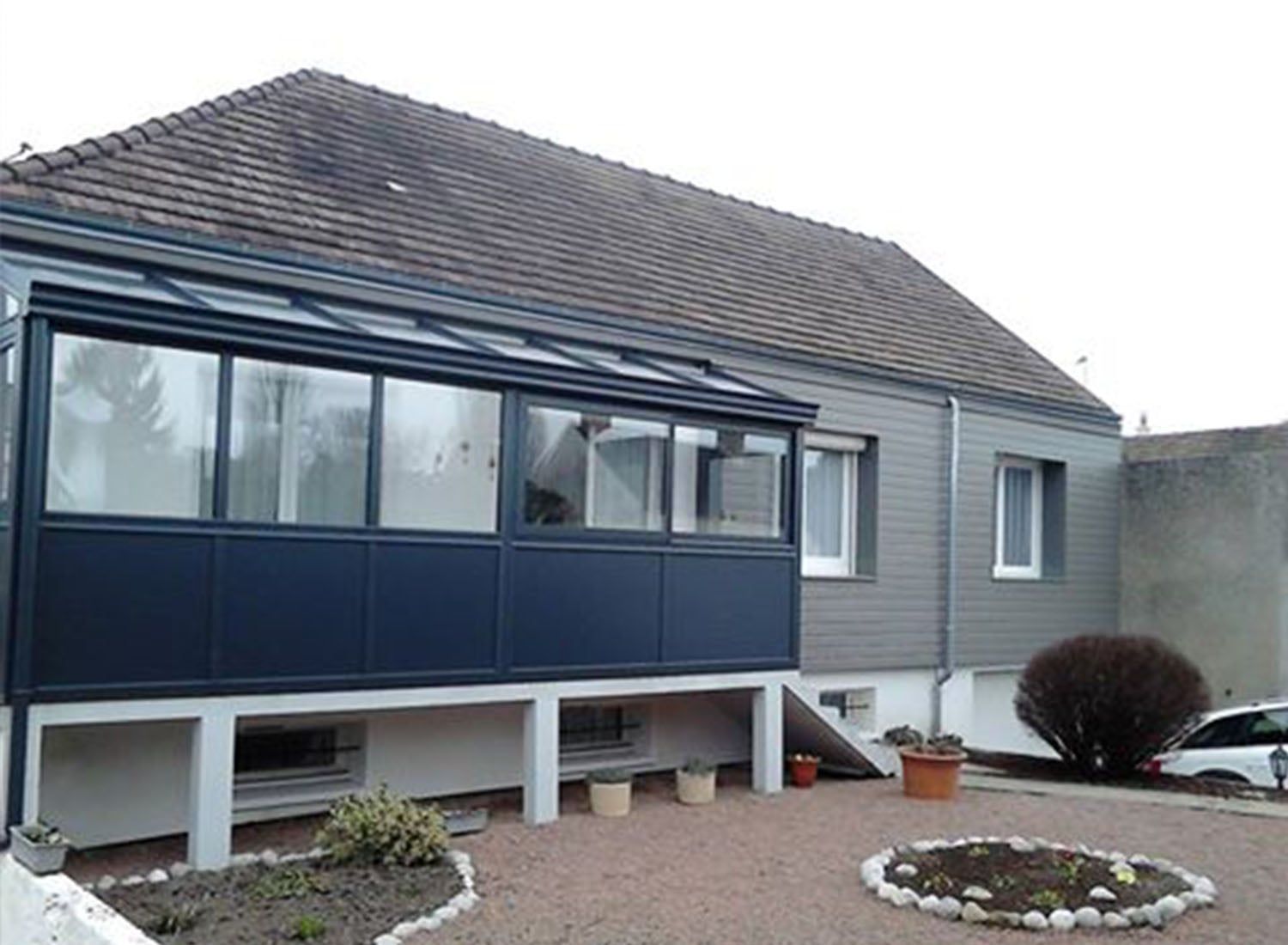 Extérieur de la maison avec bardage gris, porche bleu foncé et cour avant en gravier