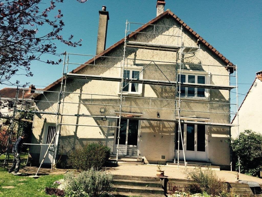 Maison à deux étages avec des échafaudages sur la façade avant et une petite cour avant.