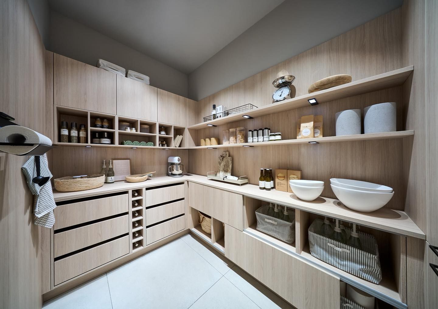 Cuisine moderne avec placards en bois clair, plan de travail blanc et étagères ouvertes pour ranger la vaisselle et les bocaux