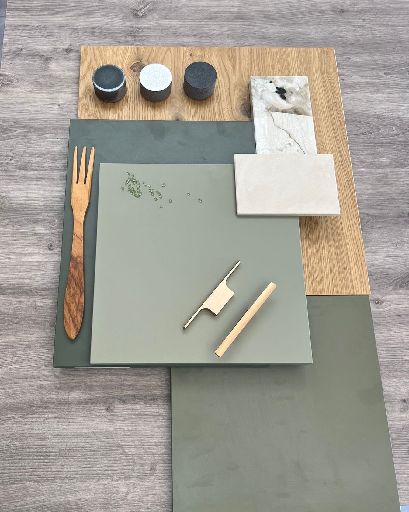 Composition d'échantillons de papiers verts et beiges, avec de petits outils, sur une surface en bois gris
