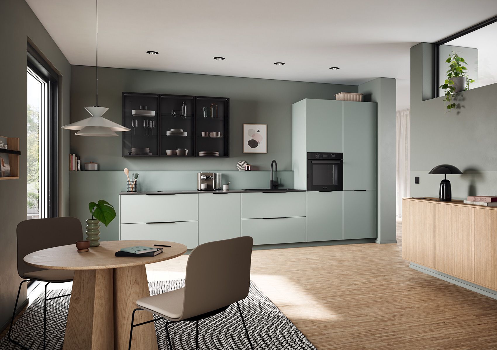 Cuisine et salle à manger ouvertes et modernes avec placards vert menthe, parquet et table ronde près d'une fenêtre
