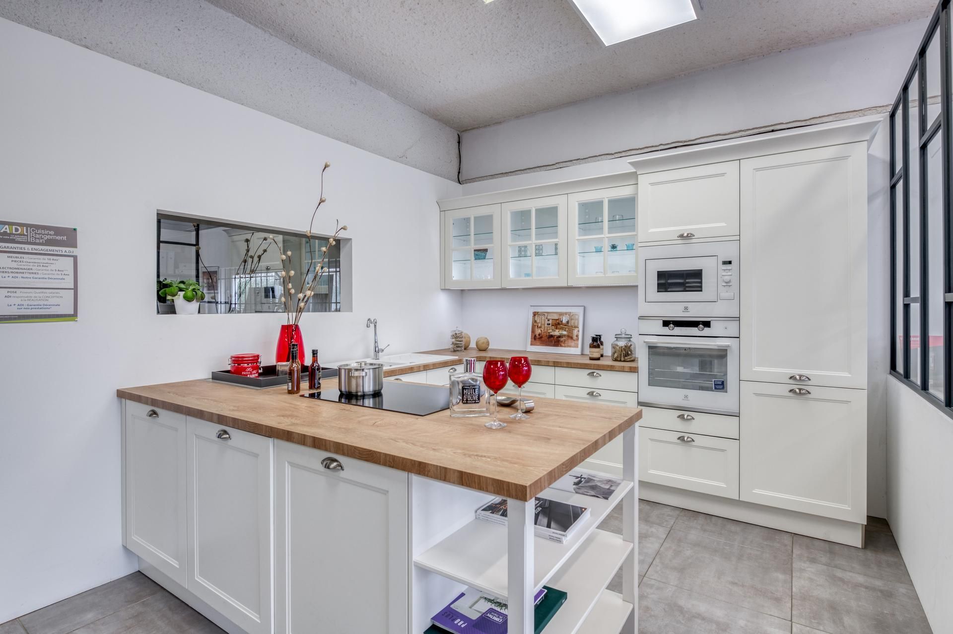 Cuisine moderne et lumineuse avec placards blancs, îlot en bois et four encastré